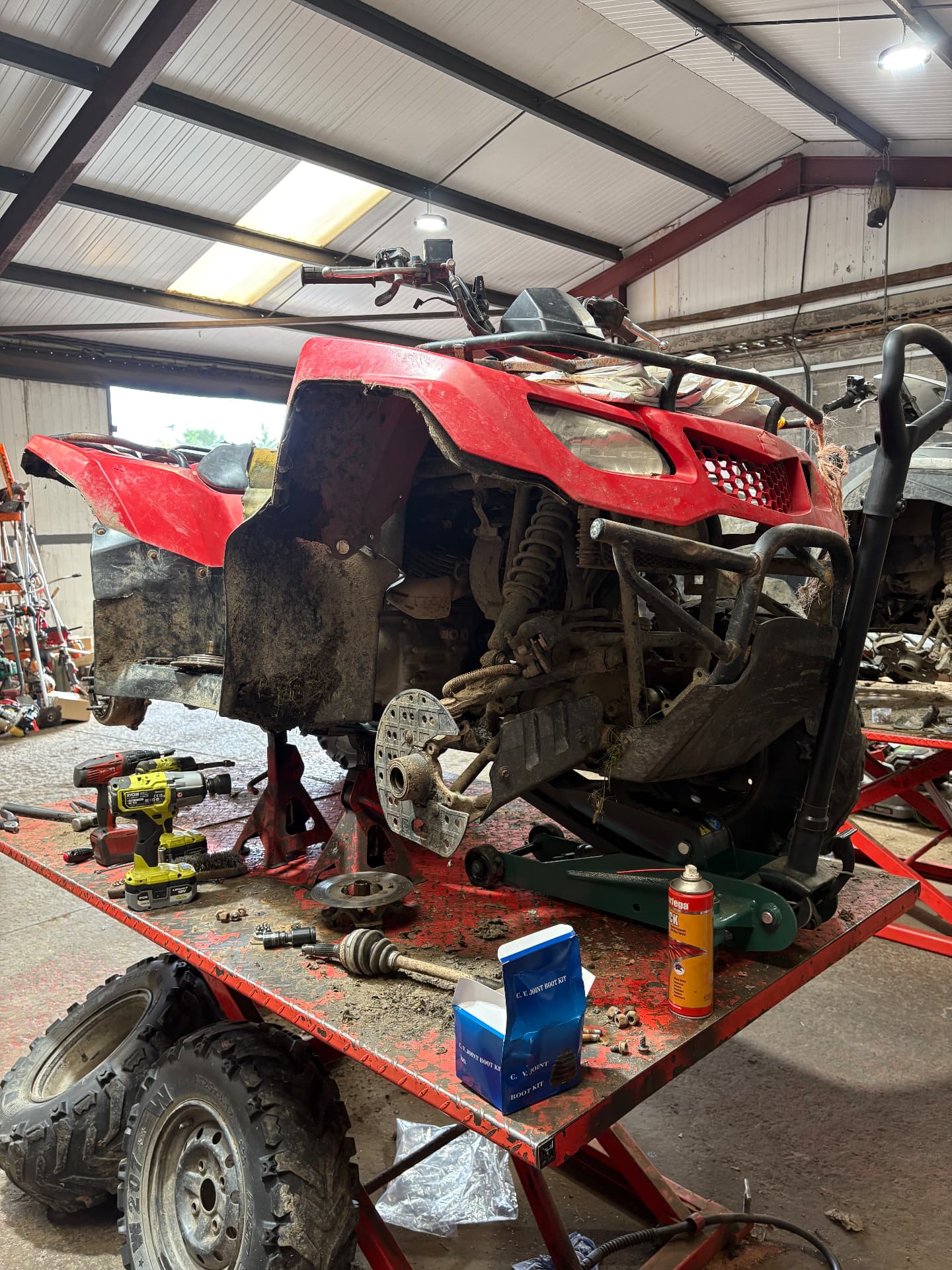 An ATV mid-repair on the ramp with tools and parts laid out